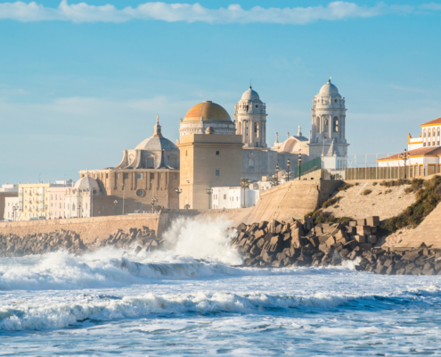View of the Ancient Cadiz Cathedral. The waves on the winter Atlantic Ocean. Spain